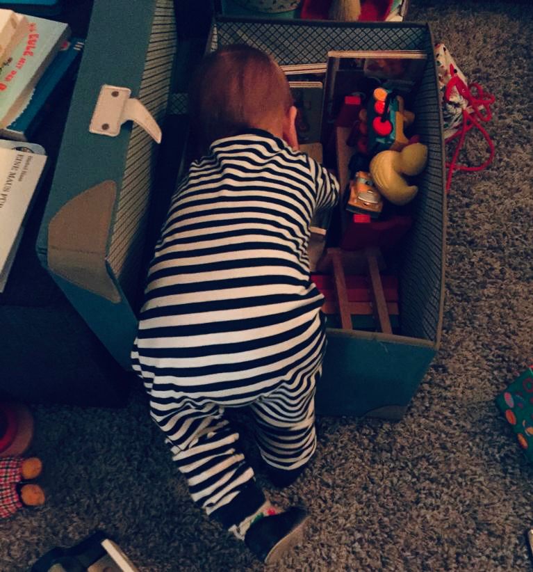 Baby erkundet eine Spielzeugkiste – Symbol für Neugier und neue Perspektiven in der offenen Sprechstunde